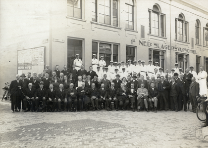 350762 Groepsportret van (leerling-)slagers en andere betrokkenen bij de Eerste Nederlandsche Slagersvakschool (Van ...